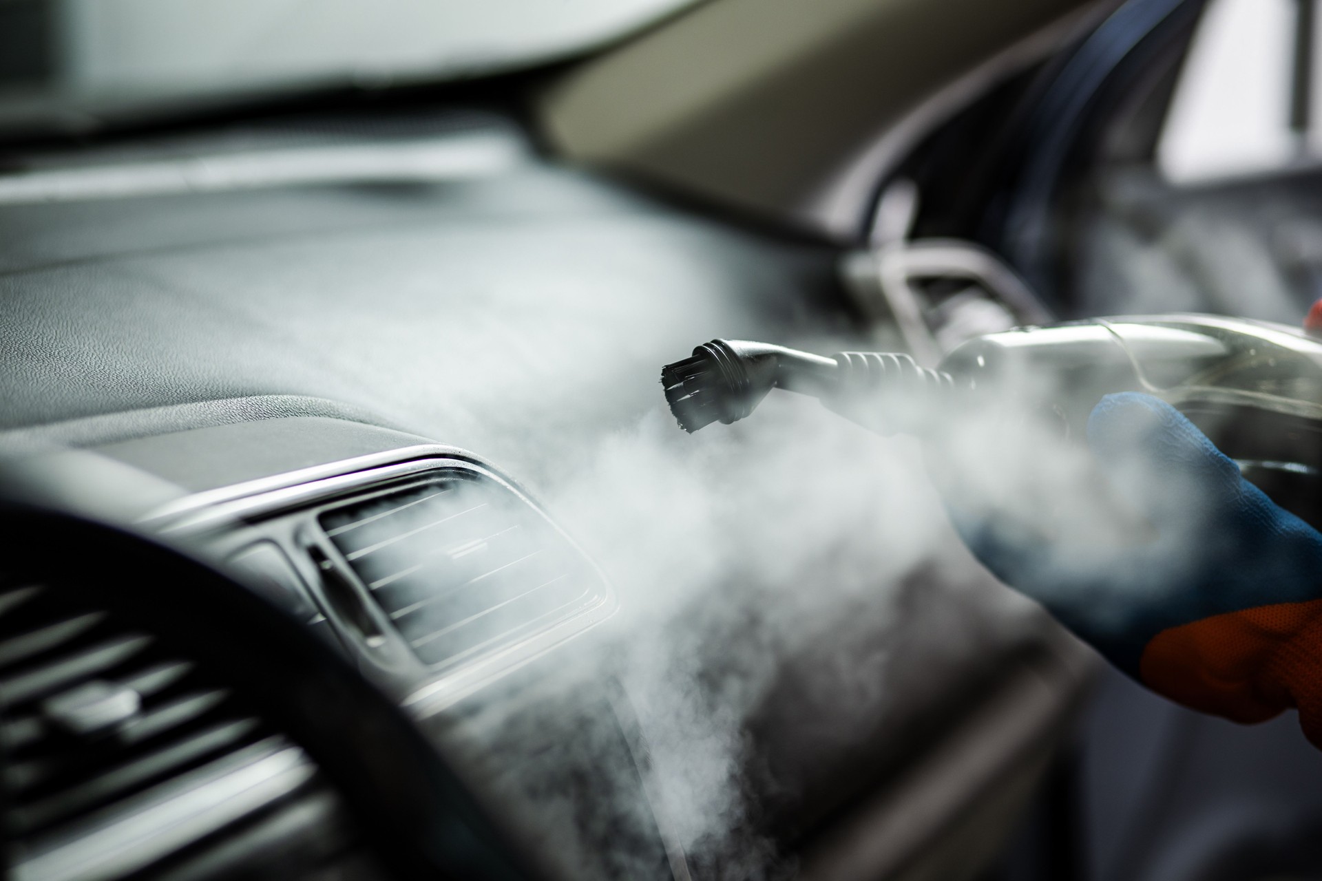 Steam cleaning the interior of a car to remove dirt and allergens at an auto detailing shop in the afternoon